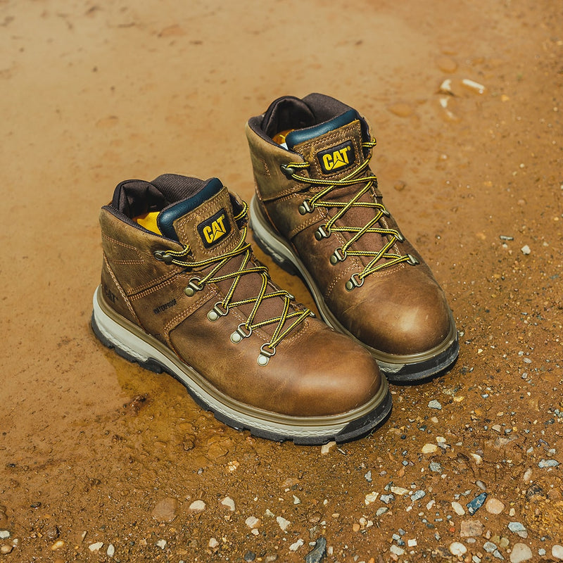 A pair of Caterpillar Exposition Hiker boots on wet mud and stones